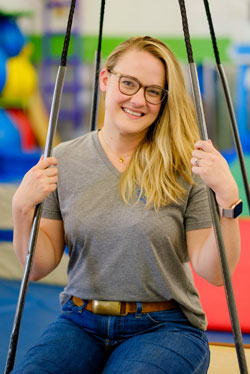 Bio picture of speech language pathologist Anna Housman on a therapy swing