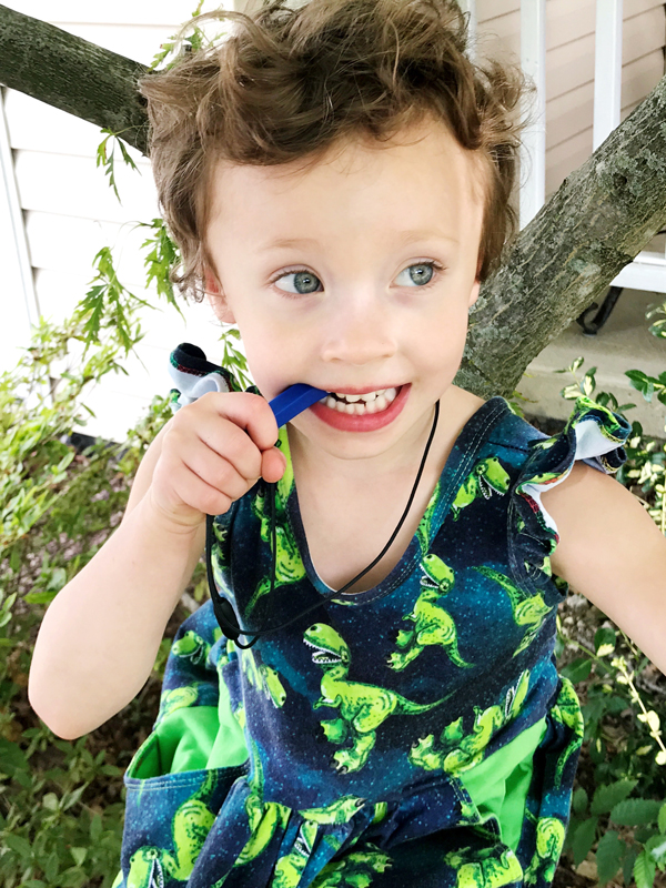 How Fidgeting Improves Focus and Self-Regulation Young girl chews on dark blue Krypto-Bite chewable gem necklace with back molars