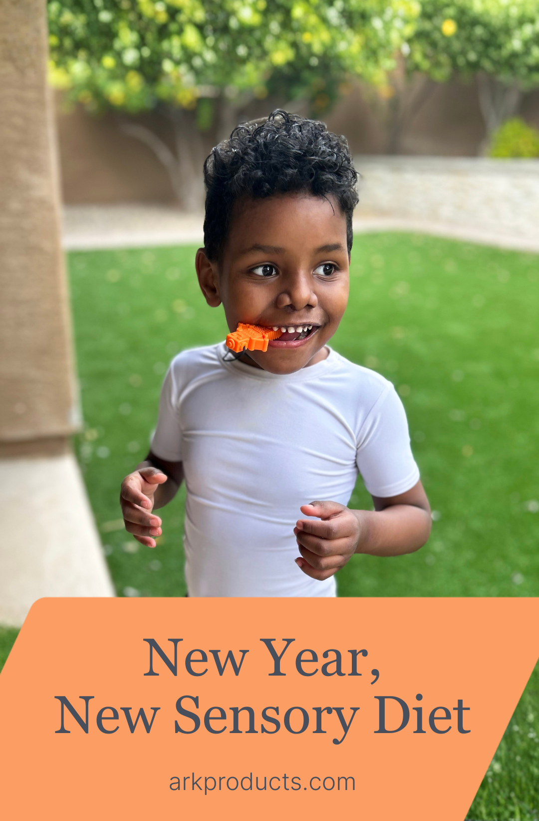 A young boy chews on an orange RoboChew Sensory Chew Necklace outside in the backyard.