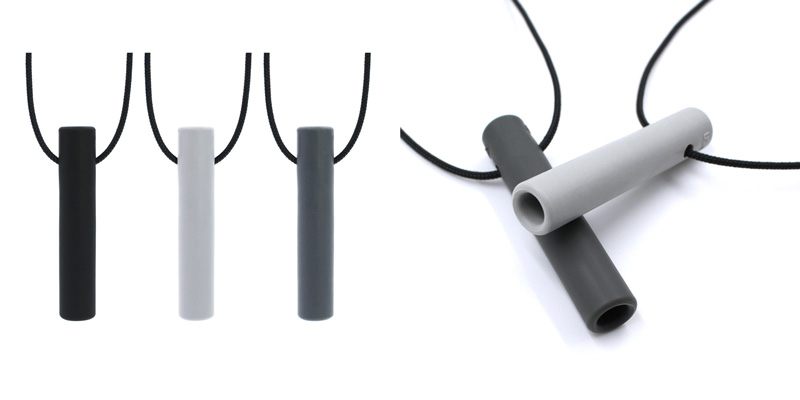 On the left: black, light grey, and dark grey Bite Tube necklaces hanging vertically.  On the right: the grey ones from a side view.