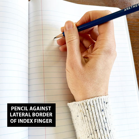 Hand demonstrating what it looks like to hold a pencil against the lateral border of index finger