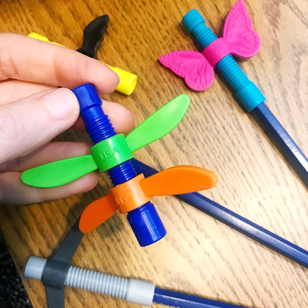 How Fidgeting Improves Focus and Self-Regulation Closeup of a hand holding the Dragonfly Wingamajig fidget with the butterfly and bat versions in the background